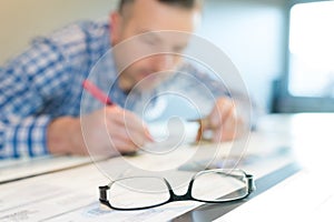 closeup eyeglasses on table man working in background