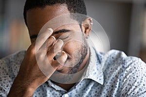 Closeup face African man rubbing eyes having vision problem