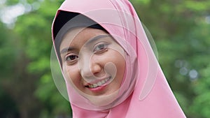 Closeup face of cheerful young woman covered with headscarf smiling outdoors. Casual Islamic girl in park. Freedom and relaxing