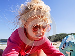 Closeup face of funny girl wearing pink sunglasses posing on beach enjoying summer travel vacation