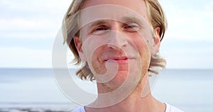 Closeup face portrait of fun and confident young man smiling and laughing with joy at holiday beach getaway. Handsome