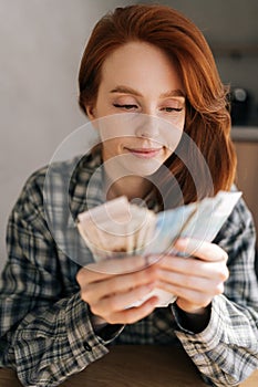 Closeup face of sad unhappy young woman counting money with sad expression, sitting at home table. Financial literacy