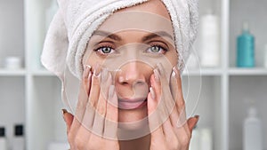 Closeup face of smiling woman applying cream on skin. Shot with RED camera in 4K