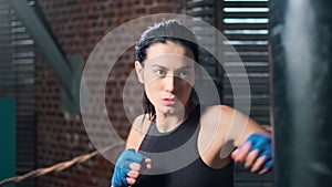 Closeup face of strong fitness lady showing beating boxing in gloves at box studio slowmo