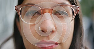 Closeup face of a woman wearing glasses to improve vision and looking serious outside on a windy day. Portrait of a