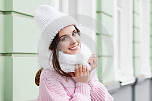 Closeup face of a young Smiling woman enjoying winter wearing knitted scarf and hat.