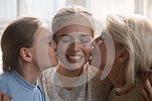 Closeup faces woman her daughter and elderly mother kiss her