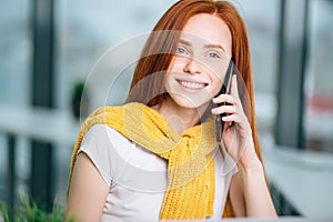 Closeup facial portrait of happy redhead woman on mobile phone call