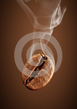 Closeup falling coffee bean with smoke on brown background