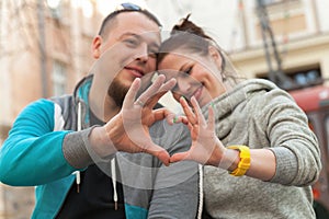 Closeup of family couple making heart shape with hands. Happy romantic young couple in love gesturing a heart with fingers, enjoyi