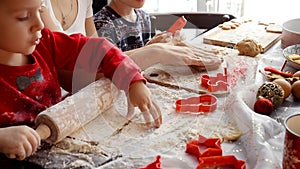 Closeup of family hands rolling dough, mixing flour and cutting out cookies and ginger bread for Christmas