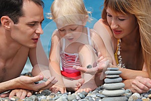 Closeup family on sea coast and pyramid of stones