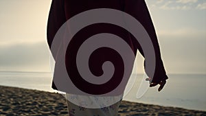 Closeup fashionable woman walking on beach. Girl spending leisure time at ocean