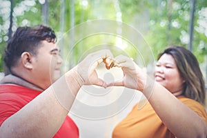 Closeup of fat Asian couple doing love hand sign