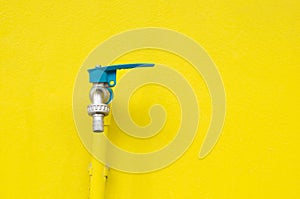 Closeup faucet on concrete Yellow wall background.