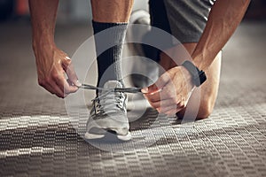 Closeup on feet of athlete tying shoe laces. Hands of bodybuilder getting ready to workout. Closeup on hands of fit man