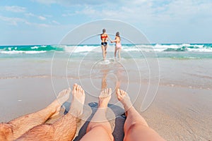Closeup of the feet of family on the white sandy beach. Children play on the beach in shallow water on summer vacation