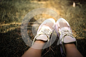 Closeup Of Feet In White Sneakers On Grass. Relaxation And Outdoor Idea Concept.