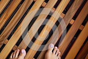 closeup of feet on wooden slats of an infrared sauna
