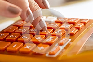 Closeup of female accountant pressing number eight on orange des