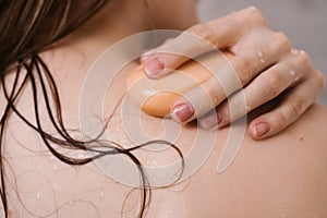 Closeup of female back with her hand on the shoulder with a bar of natural soap