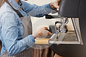 Closeup of female barista cleaning bottomless portafilter with steamer.
