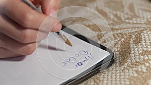 Closeup female Caucasian hand writing words in Spanish on white paper. Close-up unrecognizable woman handwriting amor