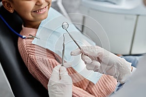 Closeup of female dentist holding tools working with child in dental clinic