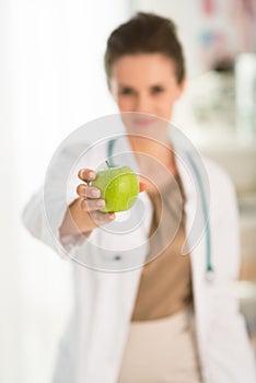 Closeup on female doctorÃÂ giving green apple photo