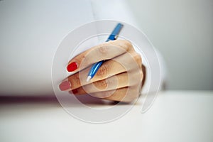 Closeup of a female doctor hands with a blue pen making notes and filling in diagnosis of patient on a paper. Coronavirus test and photo