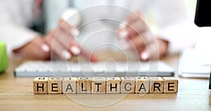 Closeup of female doctor working on laptop, typing on keyboard and text health care