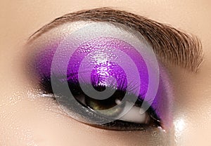 Closeup female eye with beautiful fashion bright make-up. Beautiful shiny blue eyeshadow, wet glitter, black eyeliner