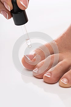 Closeup of female foot and bottle of nourishing cuticle oil with dropper