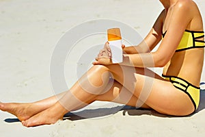 Closeup on female hand applying sun screen creme on leg. Skincare. .Sun protection sun cream, on her smooth tanned legs