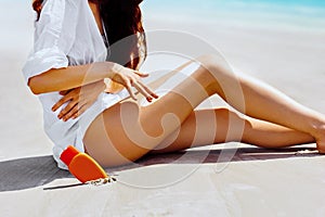 Closeup on female hand applying sun screen creme on legs.Sun Cream. Skin and Body Care.