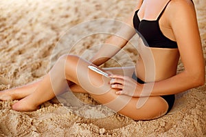 Closeup on  female hand applying sunscreen creme on beautiful legs. Skincare.