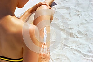Closeup on female Hand applying sunscreen creme on Leg. Skincare. .Sun protection sun cream, on her smooth tanned legs