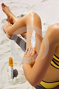 Closeup on female Hand applying sunscreen creme on Leg. Skincare. .Sun protection sun cream, on her smooth tanned legs