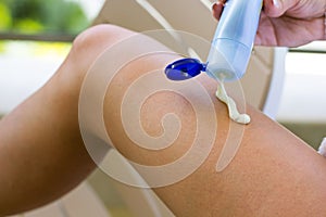 Closeup on female hand applying sunscreen on legs. Sun cream. Skincare