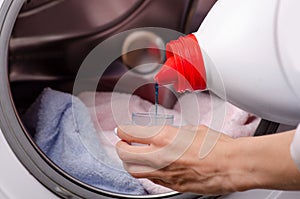 Closeup of a female hand detergent or washing liquid in the container