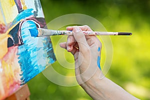 Closeup of female hand that draws picture in park. Art and hobby concept