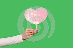 Closeup female hand holding pink heart with glitters, cute symbol of sensual feminine romantic love, greeting card