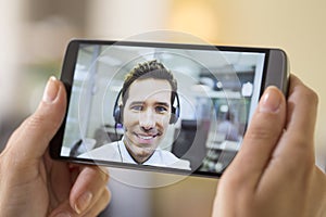 Closeup of a female hand holding a smart phone during a skype vi photo