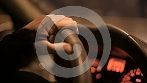 Closeup of a female hand holding the steering wheel driving a car on a country road at night. Shallow depth of field