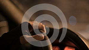 Closeup of a female hand holding the steering wheel driving a car on a country road at night. Shallow depth of field