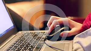 Closeup of a female hand using a computer mouse. Woman clicking mouse and scrolling website. Freelancer at home.