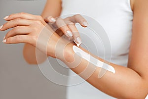 Closeup of female hands applying hand cream.Hand Skin Care. Women use body lotion on your arms. Beauty And Body Care Concept.