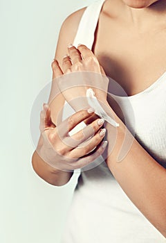 Closeup of female hands applying hand cream, lotion. Hand skin care. Beautiful woman hands with french manicure