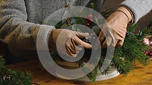 Closeup female hands decorating Christmas flower arrangement.