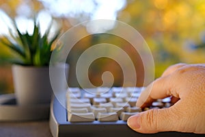 closeup female hands of elderly woman typing text on computer keyboard in garden, concept of learning to use computer at any age,